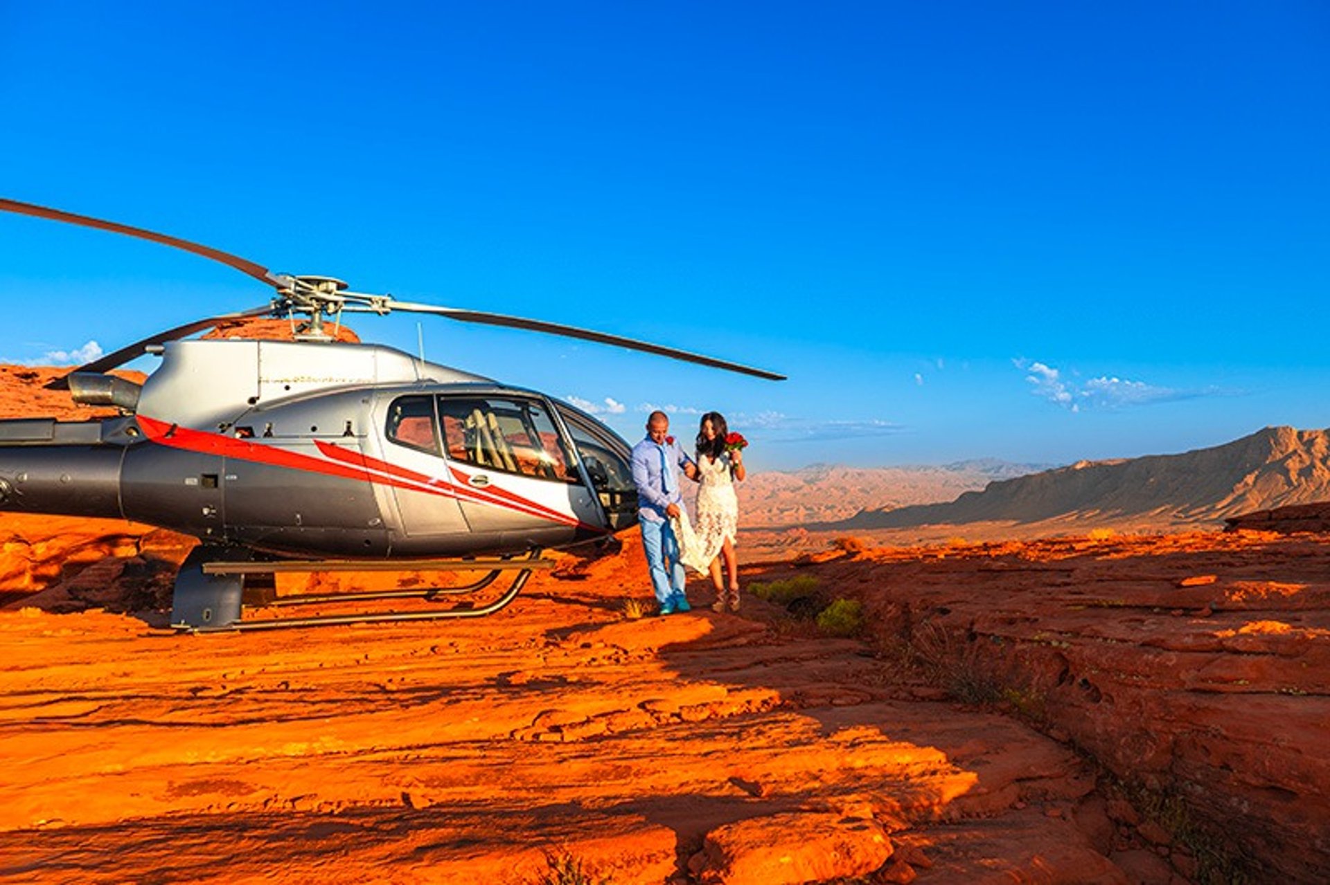 Helicopter wedding couple walking through Valley of Fire red rock plateau Nevada