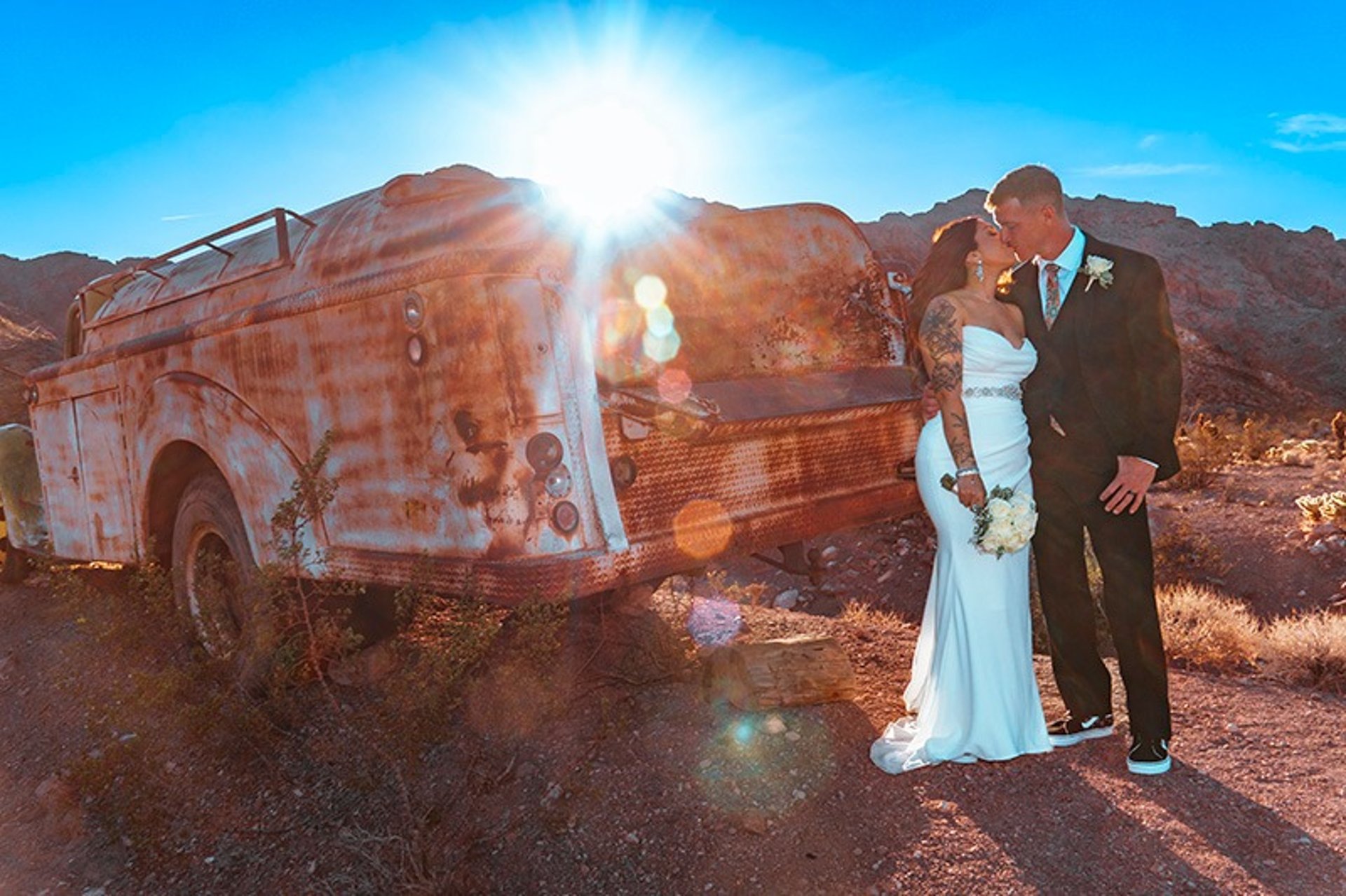 Bride and groom embracing at sunset by vintage truck at Nelson Ghost Town Nevada