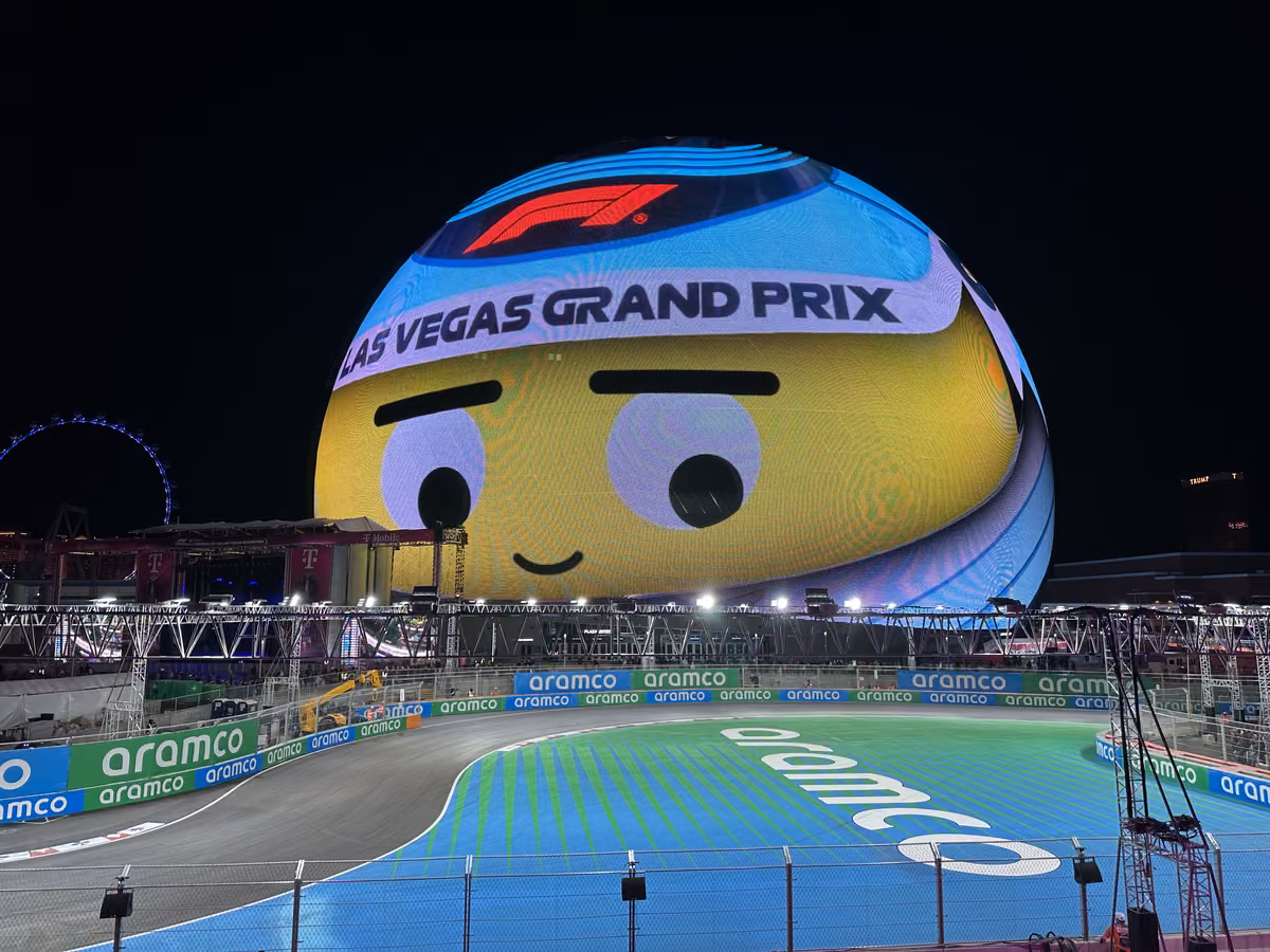 The Las Vegas Sphere lit up with a Las Vegas Grand Prix graphic above turns 7 and 8 of the street circuit at night